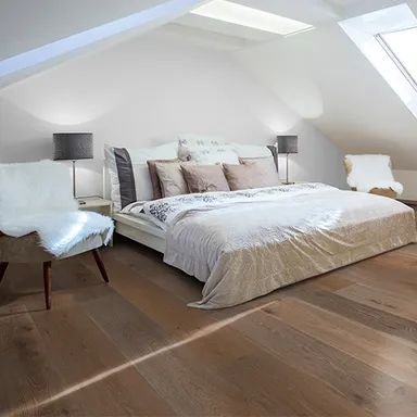 Schlafzimmer mit Bett und dunklem Parkettboden