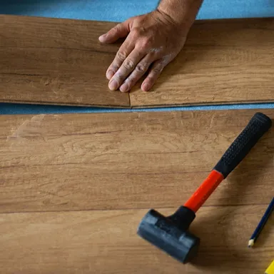 Ein heller Laminatboden von KRONOTEX der grade verlegt wird.