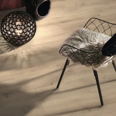 Ein moderner dunkler Stuhl der auf einem hellen Laminat mit Trittschalldämmung steht.