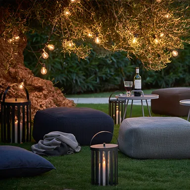 Garten eingerichtet mit Tischen und Sitzsäcken und Laternen