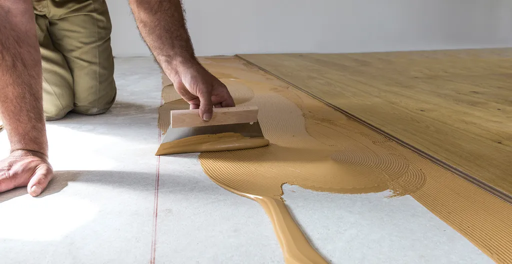 Hier ist ein Parkettboden zu sehen der verklebt Verlegt wird.