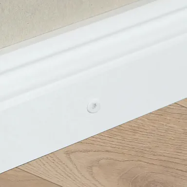 Weiße Sockelleiste wird mit Schrauben montiert.