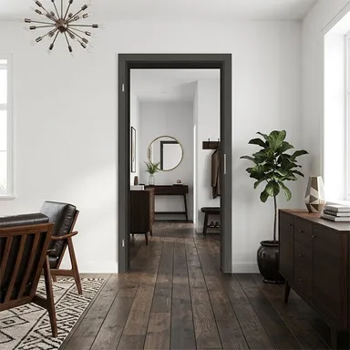 Dunkle Durchgangszarge mit Blick auf ein gemütliches, dunkel möbeliertes Wohnzimmer. 