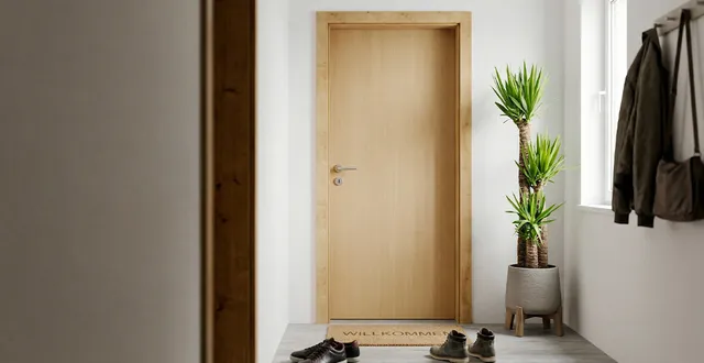 Eine helle Holzzarge für Wohnungstür die in einem hellen Flur eingebaut ist.